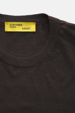 Close-up front view of B.F. Knitwear Merino Crew Neck Sweater dark violet, showing crew neckline and yellow label, made of pure merino wool, soft feel, fine knit pattern, regular fit, and comfortable ribbed cuffs.