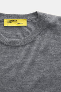 Close-up top-down view of B.F. Knitwear Merino Crew Neck Sweater grey melange showing crew neckline, pure merino wool, soft feel, fine knit pattern, regular fit, comfortable ribbed cuffs, and yellow label.