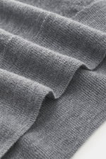 Close-up, angled view of the B.F. Knitwear Merino Crew Neck Sweater grey melange showing pure merino wool fabric with soft feel, fine knit pattern, regular fit, crew neckline, and comfortable ribbed cuffs.