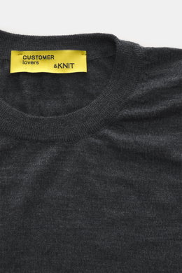 Close-up top view of the B.F. Knitwear Merino Crew Neck Sweater dark grey melange showing crew neckline and yellow label, pure merino wool, soft feel, fine knit pattern, regular fit, comfortable ribbed cuffs.