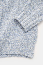 Nahaufnahme des Ärmels und Bunds des 04651/ A trip in a bag Rundhalspullover 'Donegal Cable Crew' creme/hellblau meliert, Mix aus Schurwolle und Cashmere, weicher Griff, klassisches Zopfstrick-Muster am Arm, Raglanärmel, voluminöses Strickbild, Regular Fi