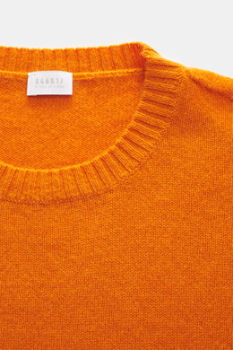 Nahaufnahme des orangefarbenen 04651/ A trip in a bag Cashmere Rundhalspullover 'Extreme Cashmere Crew' mit Rundhalsausschnitt, feinem Strick und flexiblem Rippbündchen aus reinem Cashmere, fotografiert von oben.