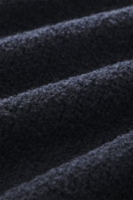 Detaillierte Nahaufnahme der weichen Bouclé-Struktur des navyfarbenen 04651/ A trip in a bag Rundhalspullovers 'Molly Crew' aus Merinowolle, Slim Fit mit flexiblem Rippbündchen, mittelfeinem Strickbild, fotografiert aus seitlicher Perspektive.