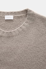 Nahaufnahme des taupefarbenen 04651/ A trip in a bag Rundhalspullover "Molly Crew" mit weicher Bouclé-Struktur, Slim Fit und Rundhalsausschnitt, fotografiert aus schräger Draufsicht.