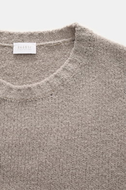 Nahaufnahme des taupefarbenen 04651/ A trip in a bag Rundhalspullover "Molly Crew" mit weicher Bouclé-Struktur, Slim Fit und Rundhalsausschnitt, fotografiert aus schräger Draufsicht.