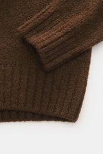 Nahaufnahme der Ärmelbündchen des 04651/ A trip in a bag Rundhalspullover 'Molly Crew' braun mit weicher Bouclé-Struktur aus Merinowolle, Slim Fit, Rundhalsausschnitt und flexiblen Rippbündchen.