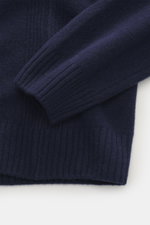 Nahaufnahme des navyfarbenen 04651/ A trip in a bag Rundhalspullover navy mit feinem Strickbild, Rippbündchen und seitlichen Rippstrick-Details, fotografiert von schräg oben.