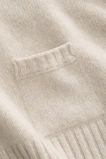 Nahaufnahme des feinen Strickbilds und der kleinen eingestrickten Tasche des 04651/ A trip in a bag Rundhalspullover sand aus Merinowolle und Cashmere.