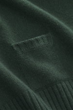 Nahaufnahme des dunkelgrünen 04651/ A trip in a bag Rundhalspullover mit feinem Strickbild, kleiner Tasche und Rippbündchen aus Merinowolle und Cashmere.