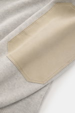Nahaufnahme des Brunello Cucinelli Cashmere Rundhalspullover hellgrau/sand meliert, Detailansicht der Veloursleder Ellenbogen-Patches, feines Strickbild, weiche Haptik sichtbar.