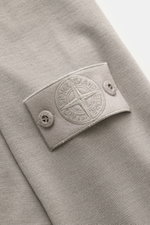 Stone Island Strickpolo 'Ghost Piece' grau aus reiner Schurwolle, weiches, feines Strickbild, tonales Kompass-Badge am Ärmel, Nahaufnahme.
