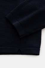 Close-up shot of the Stone Island Strickpolo navy, showing fine navy cotton knit, double-hemmed edges, and side slits from a top-down perspective. Style trifft auf lässigen Komfort: Dieses Strickpolo überzeugt mit fein strukturiertem Strick aus reiner Bau