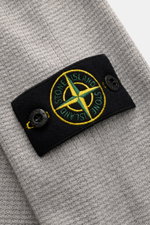 Close-up from above of the Stone Island Strickpolo grau showing the finely structured gray knit with the iconic black and yellow compass badge on the upper arm, made of pure cotton with a lightly textured feel, regular fit, classic polo collar, smooth but