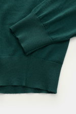 Nahaufnahme des von Braun Merino Feinstrickpolo dunkelgrün, zeigt glatte Rippbündchen und feines Strickbild aus reiner Merinowolle.