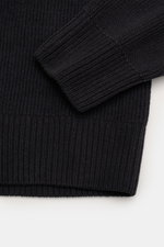 Nahaufnahme des C.P. Company Strickpolo navy, fotografiert aus seitlicher Perspektive, zeigt weichen, schweren Baumwoll-Chenille-Strick mit Rippbündchen und Linsen-Detail am Ärmel.