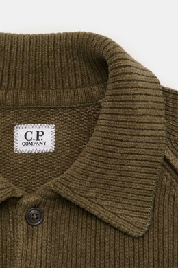 Nahaufnahme des olivfarbenen C.P. Company Strickpolo aus schwerer Baumwoll-Chenille, mit Rippstrickkragen und Label-Detail, von oben fotografiert.
