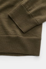Nahaufnahme des Stone Island Strickpolo 'Ghost Pure Light Wool' dark olive, Fokus auf weiches Rippbündchen aus reiner Schurwolle mit feinem Strickbild.