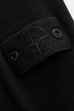 Nahaufnahme des schwarzen Stone Island Strickpolo 'Ghost Pure Light Wool' vom Oberarm, zeigt Kompass-Badge, reine Wolle, weichen Griff, feines Strickbild, Regular Fit, Umlegekragen und Rippbündchen.