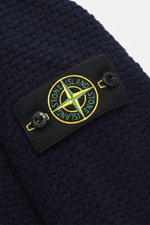 Nahaufnahme des Stone Island Cardigan navy von schräg oben, zeigt das voluminöse Strickbild, Mix aus Schurwolle und Microfaser, Kompass-Badge am Oberarm, Regular Fit, Umlegekragen, Fünf-Knopf-Leiste und komfortable Ärmelbündchen mit leicht kernigem Griff.