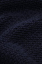 Nahaufnahme des voluminösen Strickbilds des Stone Island Cardigan navy, Mix aus Schurwolle und Microfaser, Regular Fit, Umlegekragen, 5-Knopf-Leiste, Ärmelbündchen und Kompass-Badge am Oberarm, fotografiert aus frontaler Perspektive.
