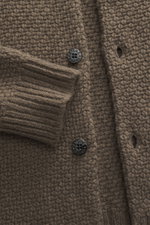 Nahaufnahme des Stone Island Cardigan braun, Frontansicht mit voluminösem Strickbild, kernigem Griff, Fünf-Knopf-Leiste und Ärmelbündchen.
