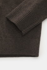 Nahaufnahme des Stone Island Strickpolo dunkelbraun meliert, Detail von Ärmelbündchen, reine Schurwolle, feines Strickbild, weiche Qualität, Regular Fit, gestrickter Polokragen, Zwei-Knopf-Leiste, STONE ISLAND-Weblabel, elastische Bündchen.