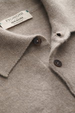 Nahaufnahme des Fioroni Cashmere Strickpolo taupe meliert aus reinem Baby-Cashmere, fein gestrickt mit Polokragen, drei Knöpfen und flexiblen Rippbündchen, fotografiert aus schräger Perspektive.