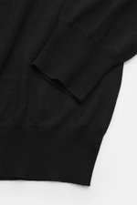 Gran Sasso Fine knit polo black close-up of sleeve and body, photographed from above, showing fine knit texture, ribbed cuffs, and smooth lightweight fabric. The lightweight knit polo by GRAN SASSO is made from ultra-fine virgin wool, cashmere, and silk. 