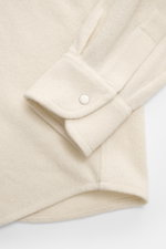 Nahaufnahme des Ärmels mit Sportmanschette und Druckknopf des B.F. Knitwear Cashmere Strickhemd Kent-Kragen creme aus weichem, feinem Strick in Slim Fit, von oben fotografiert.
