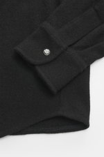 Nahaufnahme des schwarzen B.F. Knitwear Cashmere Strickhemds Kent-Kragen, zeigt weiche, feine Strickmanschette mit Druckknopf, gerundeter Saum.