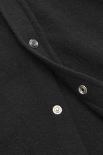 Nahaufnahme aus schräger Perspektive des schwarzen B.F. Knitwear Cashmere Strickhemds Kent-Kragen mit feinem Strickbild und Druckknopfleiste.