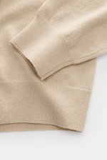 Nahaufnahme des beigen Della Ciana Troyer, fotografiert von oben auf Ärmel und Bund, mit weichem Griff, feinem Strickbild, Regular Fit, Troyer-Kragen mit Reißverschluss und flexiblen Rippbündchen, Mix aus Cashmere und Merinowolle.