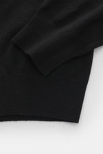 Della Ciana Troyer schwarz, Nahaufnahme der Ärmel und Saum, Mix aus Cashmere und Merinowolle, weicher Griff, feines Strickbild, Regular Fit, Troyer-Kragen mit Reißverschluss, flexible Rippbündchen, flach liegende Perspektive.