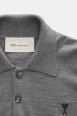 Nahaufnahme von Ami Paris Merino Strickpolo grau meliert aus reiner Merinowolle, weicher Griff, feines Strickbild, Regular Fit, typischer Polokragen, Drei-Knopf-Leiste, elastische Rippbündchen, Logo-Stitching auf der Brust, frontal fotografiert.