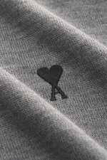 Nahaufnahme des feinen Strickbilds und Logo-Stitchings auf der Brust des Ami Paris Merino Strickpolo grau meliert, reine Merinowolle, weicher Griff, Regular Fit, typischer Polokragen, Drei-Knopf-Leiste, elastische Rippbündchen, fotografiert aus schräger P