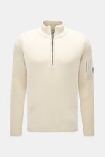 C.P. Company Troyer creme, frontale Nahaufnahme, Strick aus Schurwolle und Microfaser, weicher Griff, mittelfeines Strickbild, Slim Fit, Troyer-Kragen mit Reißverschluss, Tasche mit Zipper am Oberarm, Linsen-Detail, flexible Rippbündchen.