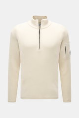 C.P. Company Troyer creme, frontale Nahaufnahme, Strick aus Schurwolle und Microfaser, weicher Griff, mittelfeines Strickbild, Slim Fit, Troyer-Kragen mit Reißverschluss, Tasche mit Zipper am Oberarm, Linsen-Detail, flexible Rippbündchen.