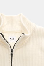 C.P. Company Troyer creme, Nahaufnahme von oben, Strick aus Schurwolle und Microfaser, weicher Griff, mittelfeines Strickbild, Patentmuster, Slim Fit, Troyer-Kragen mit Reißverschluss, Tasche mit Zipper am Oberarm, Linsen-Detail, flexible Rippbündchen.