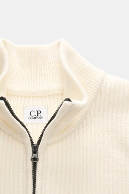 C.P. Company Troyer creme, Nahaufnahme von oben, Strick aus Schurwolle und Microfaser, weicher Griff, mittelfeines Strickbild, Patentmuster, Slim Fit, Troyer-Kragen mit Reißverschluss, Tasche mit Zipper am Oberarm, Linsen-Detail, flexible Rippbündchen.