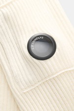 Nahaufnahme des labeltypischen Linsen-Details am Oberarm des C.P. Company Troyer creme mit mittelfeinem, weichem Strick aus Schurwolle und Microfaser.
