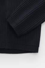 Nahaufnahme des Ärmels und Bunds des C.P. Company Troyer navy, fotografiert von oben, Strick aus Schurwolle und Microfaser, weicher Griff, mittelfeines Strickbild, markantes Patent-Strickmuster, Slim Fit, Troyer-Kragen mit Reißverschluss, Tasche mit Zippe