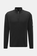 C.P. Company Troyer anthrazit in Frontansicht, mittelfeines Strickbild, Patent-Strickmuster, Slim Fit, Troyer-Kragen mit Reißverschluss, Tasche mit Zipper am Oberarm, Schurwolle/Microfaser, weicher Griff, flexible Rippbündchen, Linsen-Detail.