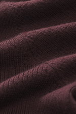 Nahaufnahme des feinen Strickbilds in Bordeaux des Kiefermann Merino Strickpolo 'Imano' mit weichem Griff, Oversized Fit, Polokragen und Drei-Knopf-Leiste, reine Merinowolle, aus schräger Perspektive.