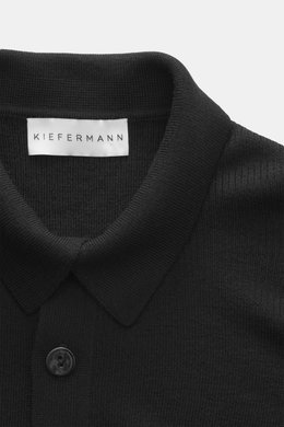 Nahaufnahme von Kiefermann Merino Strickpolo 'Imano' schwarz, reine Merinowolle, weicher Griff, feines Strickbild, Oversized Fit, typischer Polokragen, Drei-Knopf-Leiste, von oben fotografiert.