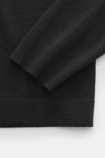Nahaufnahme des schwarzen Kiefermann Merino Strickpolo 'Imano' mit feinem Strickbild, weichem Griff, Oversized Fit, Polokragen und Drei-Knopf-Leiste, fotografiert von oben. Reine Merinowolle.