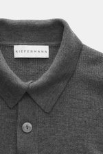 Nahaufnahme aus Frontperspektive des Kiefermann Merino Strickpolo 'Imano' dunkelgrau mit typischem Polokragen, Drei-Knopf-Leiste, feinem Strickbild, weichem Griff, Oversized Fit, aus reiner Merinowolle.