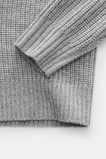 Nahaufnahme des Allude Troyer grau meliert, fotografiert von oben, zeigt Patentstrick aus Wolle und Cashmere, weichen Griff, mittelgrobes Strickbild, Slim Fit, Rippstrickkragen mit Zipper und komfortable Rippbündchen.
