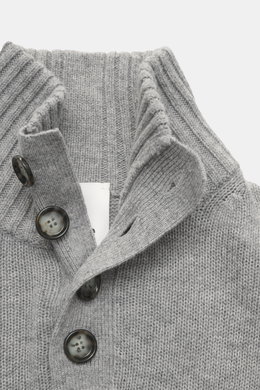 Nahaufnahme des Allude Troyer grau meliert, fotografiert aus leicht seitlicher Draufsicht, mit Stehkragen, Vier-Knopf-Leiste, mittelgrobem Strickbild, Regular Fit, weichem Griff, Mix aus Schurwolle und Cashmere sowie komfortablen Rippbündchen.