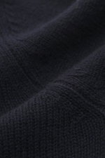 Nahaufnahme des mittelgroben Strickbilds vom Allude Troyer navy, Mix aus Schurwolle und Cashmere, weicher Griff, Regular Fit, Stehkragen mit Vier-Knopf-Leiste, komfortable Rippbündchen, fotografiert aus Seitenperspektive.