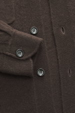 Nahaufnahme des dunkelbraunen Allude Strickhemds aus Schurwolle und Cashmere, weicher Griff, feines Strickbild, Regular Fit, Umlegekragen, glatte Knopfleiste, aufgesetzte Brusttaschen, komfortable Rippbündchen, fotografiert von oben.